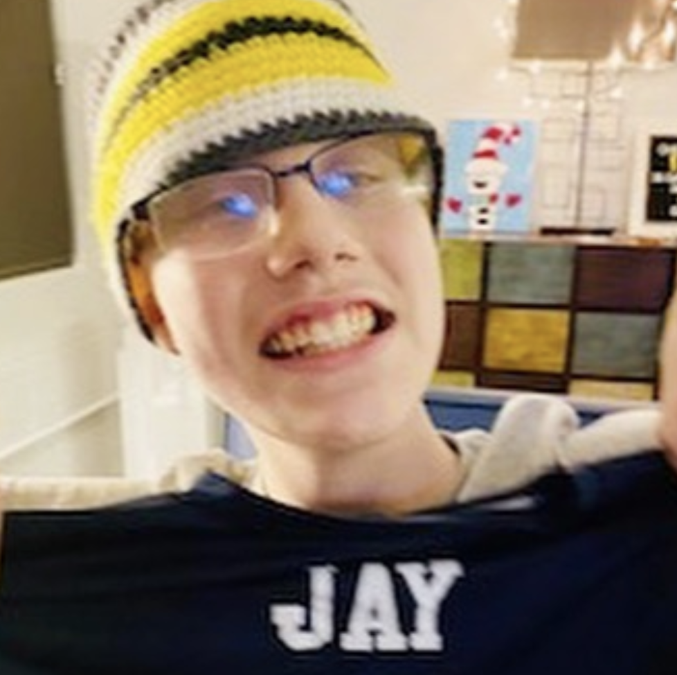 Cancer Kickers Teammate Jay smiling and holding up blue custom name t-shirt with cancer kickers logo nike label