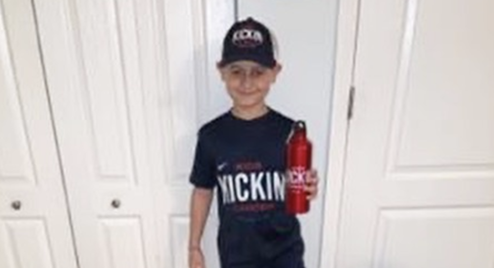Cancer Kickers Teammate Braiden holding water bottle with logo wearing hat player kit nike label