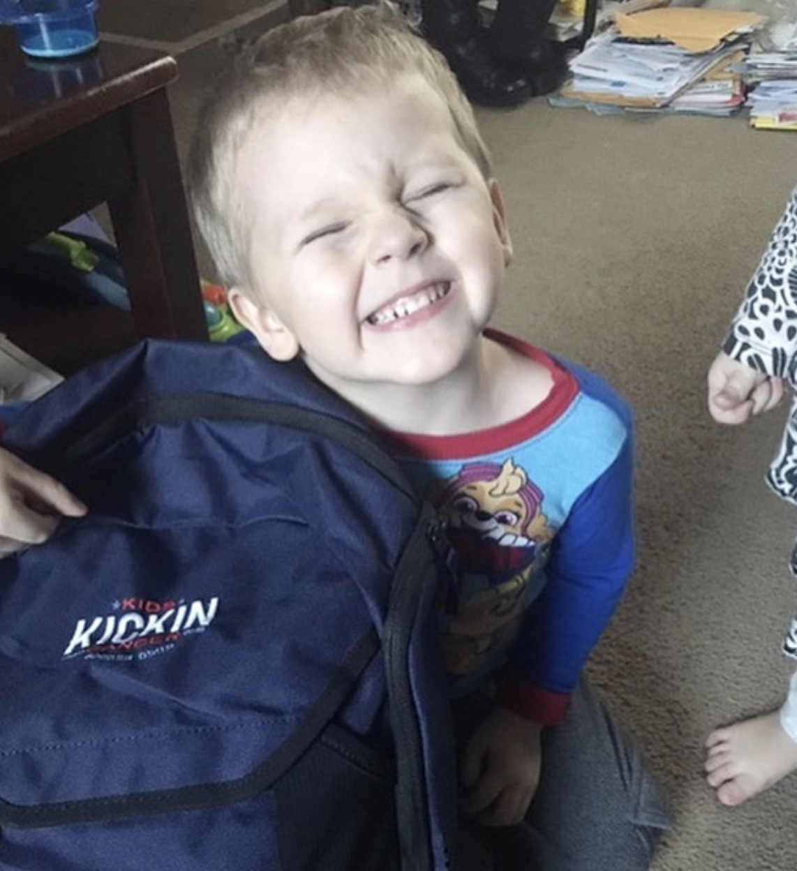Cancer Kickers Teammate Kayjay grinning and holding player kit backpack with logo nike label