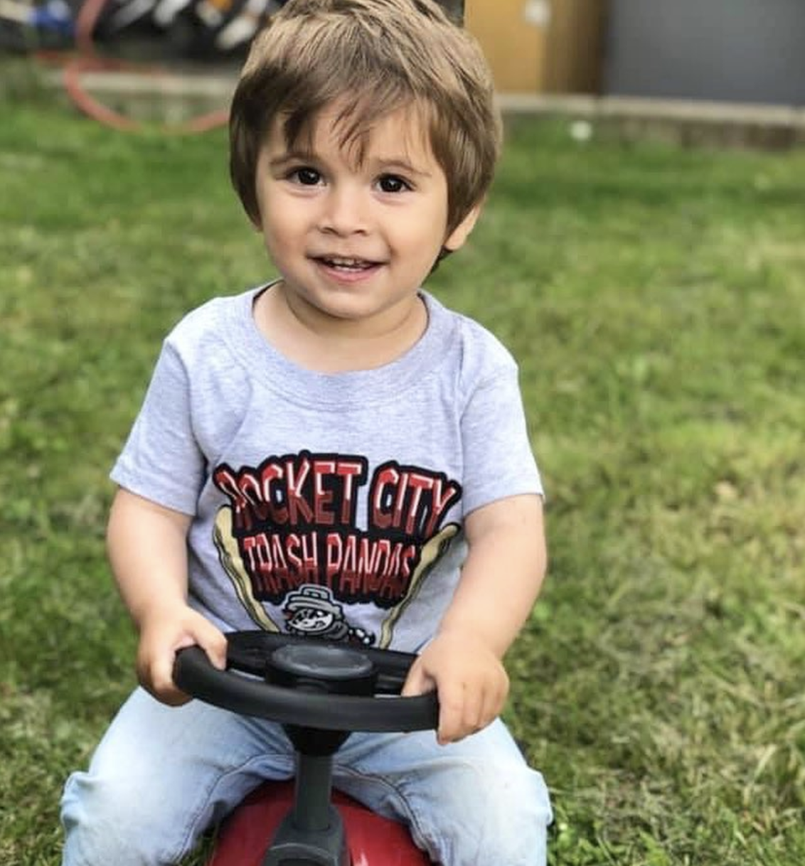 Cancer Kickers Teammate Griffin smiling riding a toy car