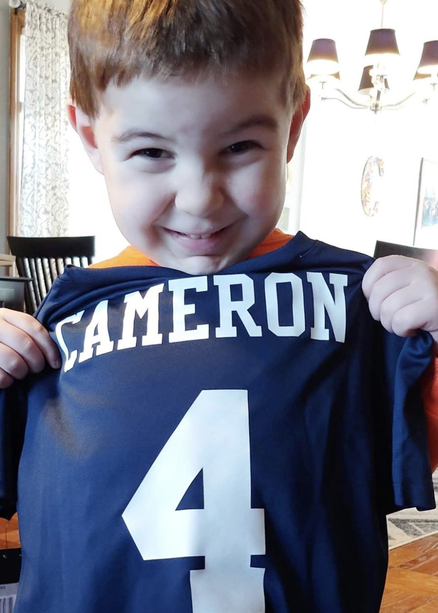 Cancer Kickers Teammate Cameron holding nike jersey with custom name and number on back