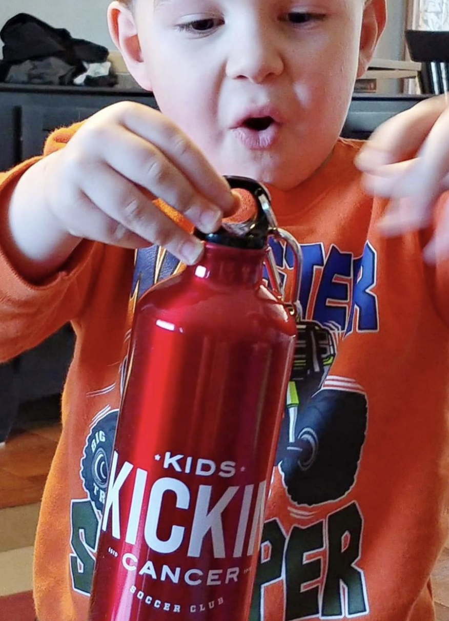 Cancer Kickers Teammate Cameron holding water bottle with cancer kickers logo